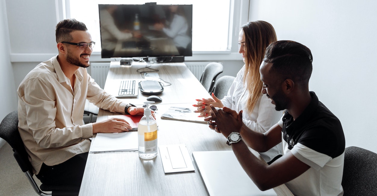 Three people at a long table for a business meeting