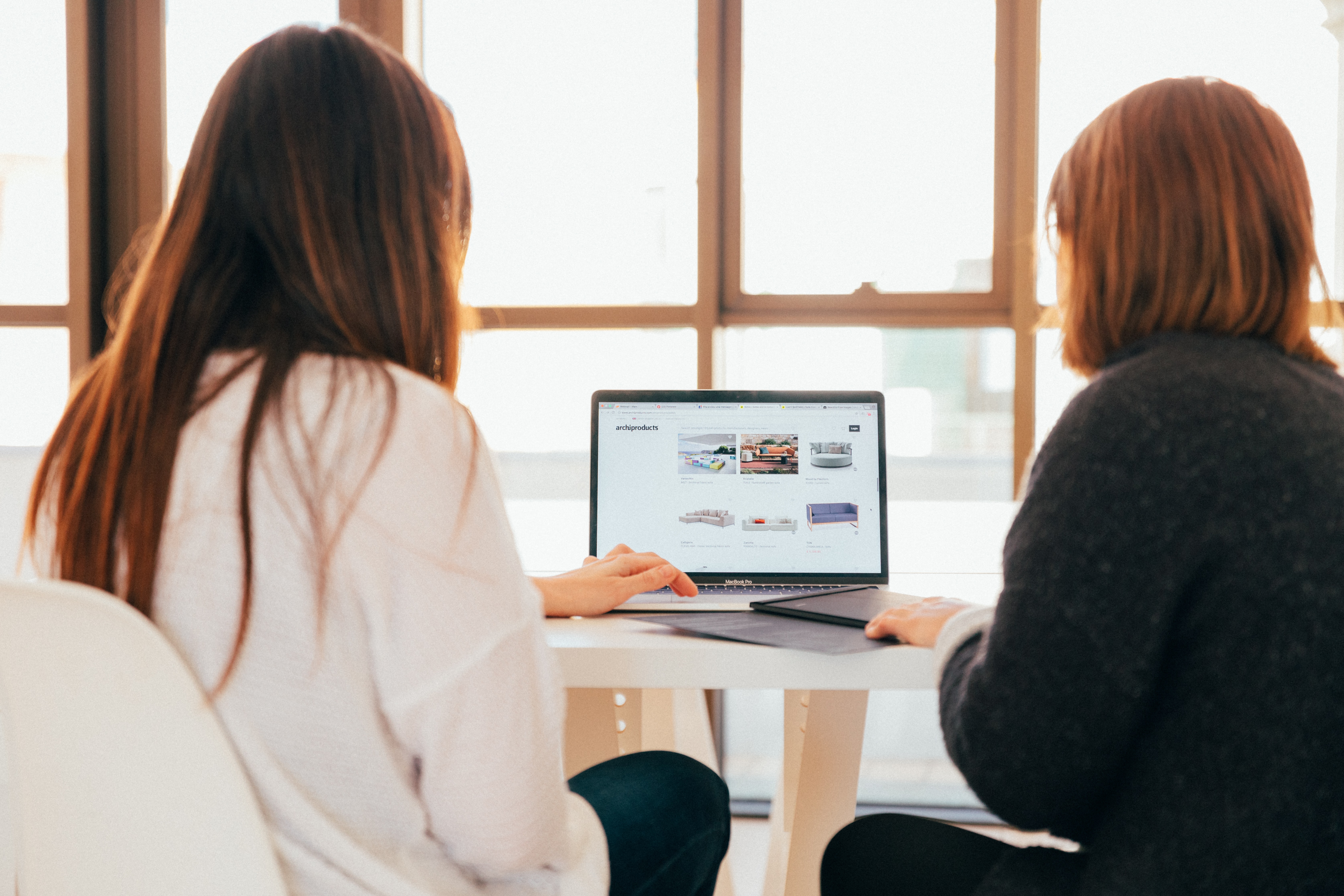 Two women sitting in front of a laptop working on a project.