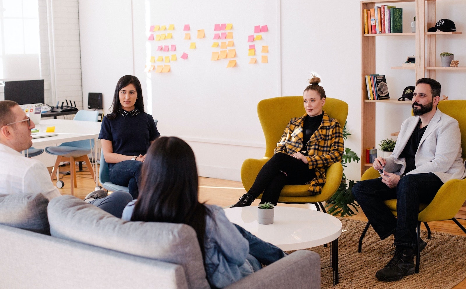 Five colleagues sitting around a coffee table in a modern office having a meeting.