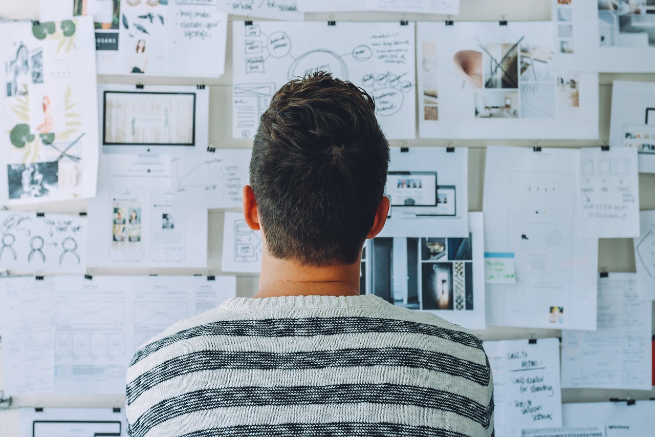 Individual with short hair facing away from the camera and looking at a strategy board. 